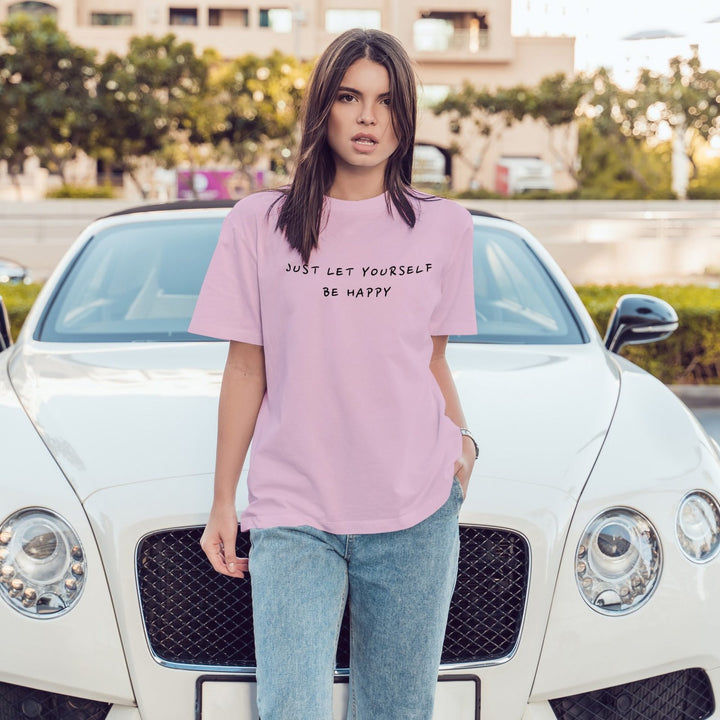 Juxar baggy boyfriend t shirt light pink with motivational print worn by model over jeans in front of white car
