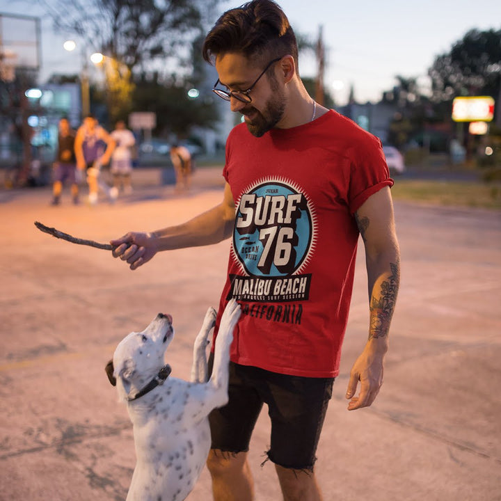 Juxar cotton t shirt with minimal print featuring a red surf design worn by a man playing with a dog