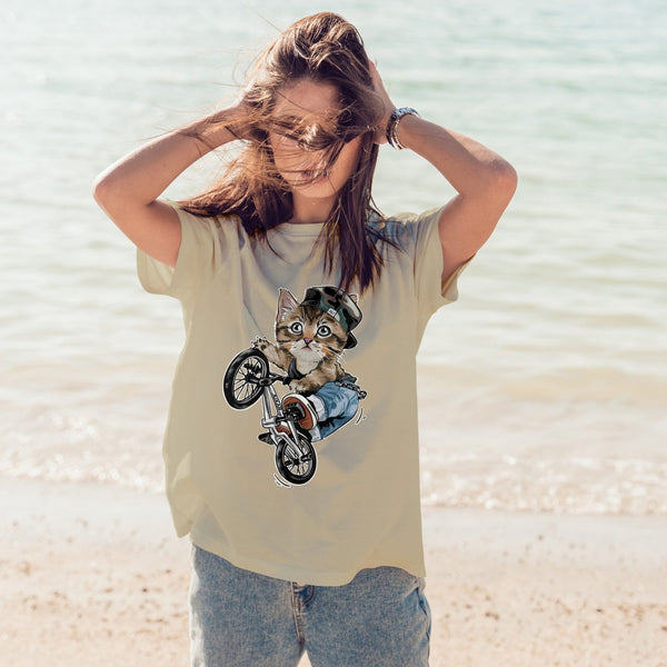 Juxar boyfriend fit printed t shirt featuring a cat on a bike graphic worn by woman at the beach
