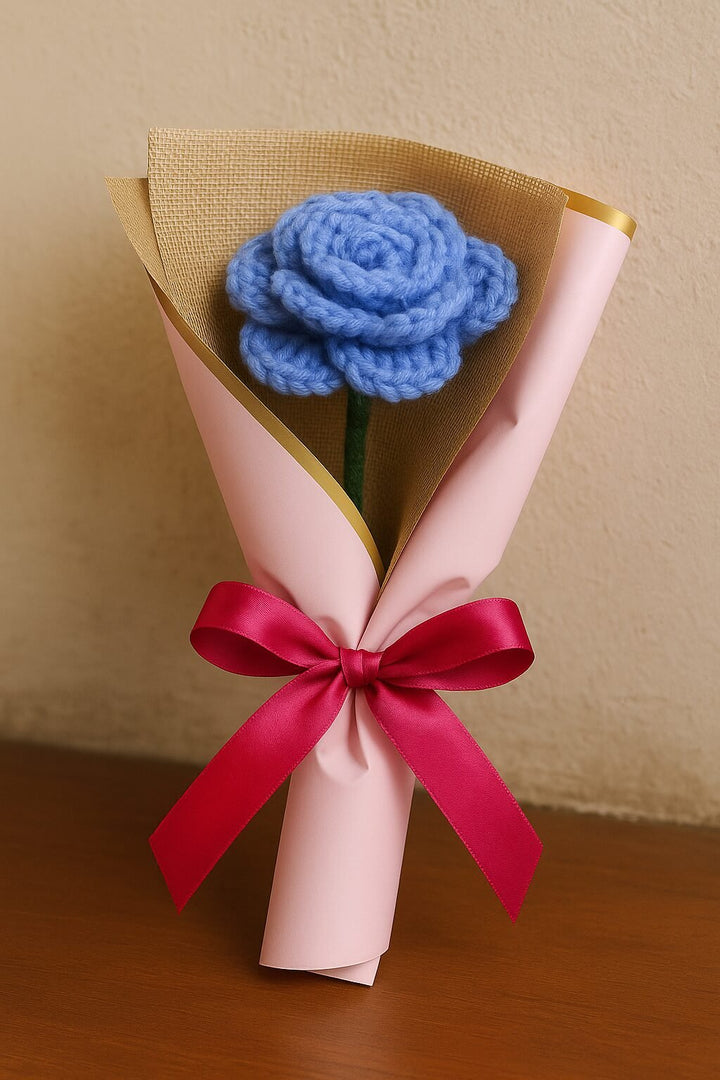 Handmade crochet rose bouquet with blue flower wrapped in pink paper and tied with red ribbon