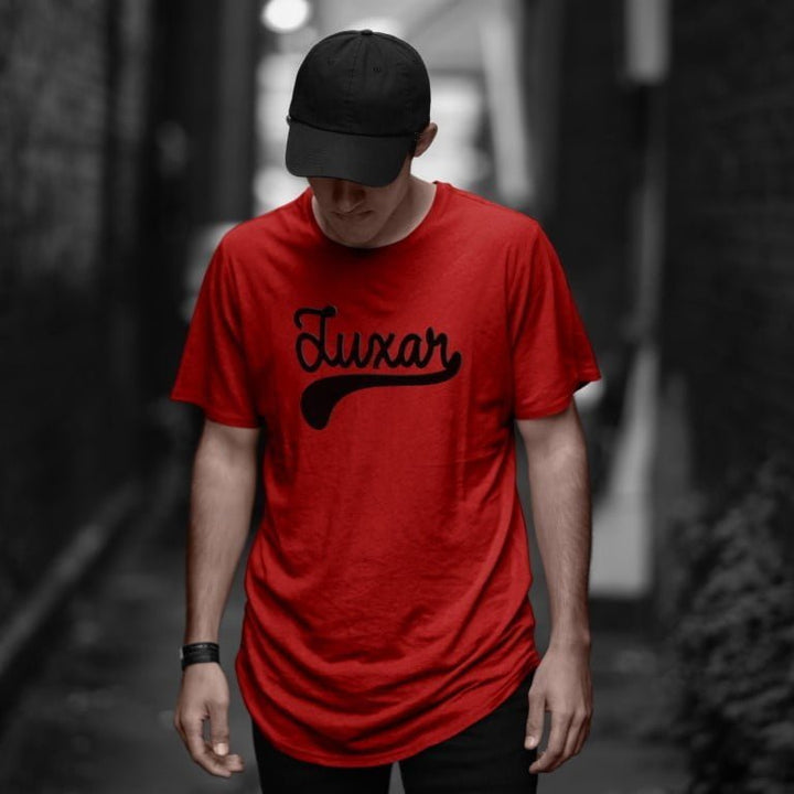 Juxar red cotton longline t shirt with script logo worn by man in black cap urban alleyway casual streetwear