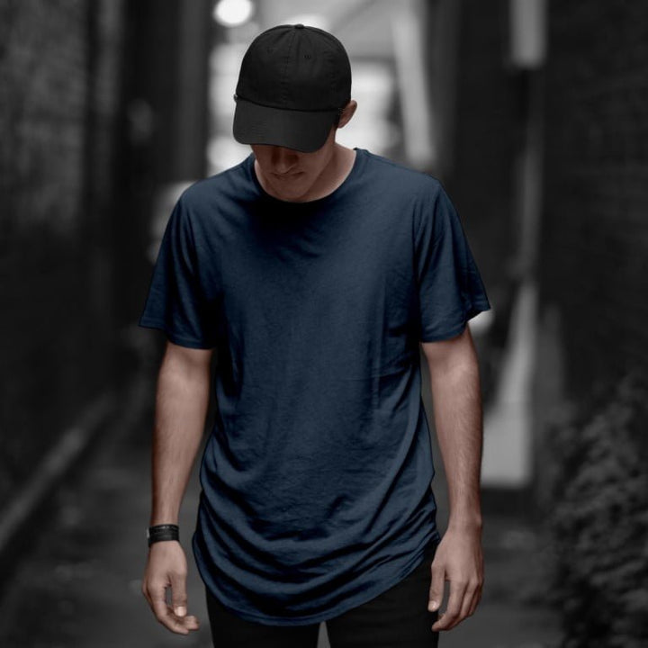 Juxar soft cotton longline tee for everyday wear modeled by a man in navy tee and black cap in an alley