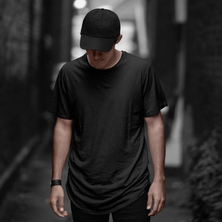Juxar black longline cotton tee on male model wearing cap in alley soft cotton longline tee for everyday wear