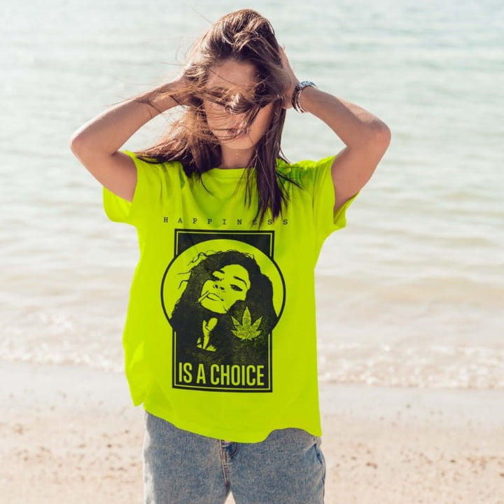 Woman on beach wearing Juxar neon green happiness boyfriend t-shirt with graphic reading is a choice